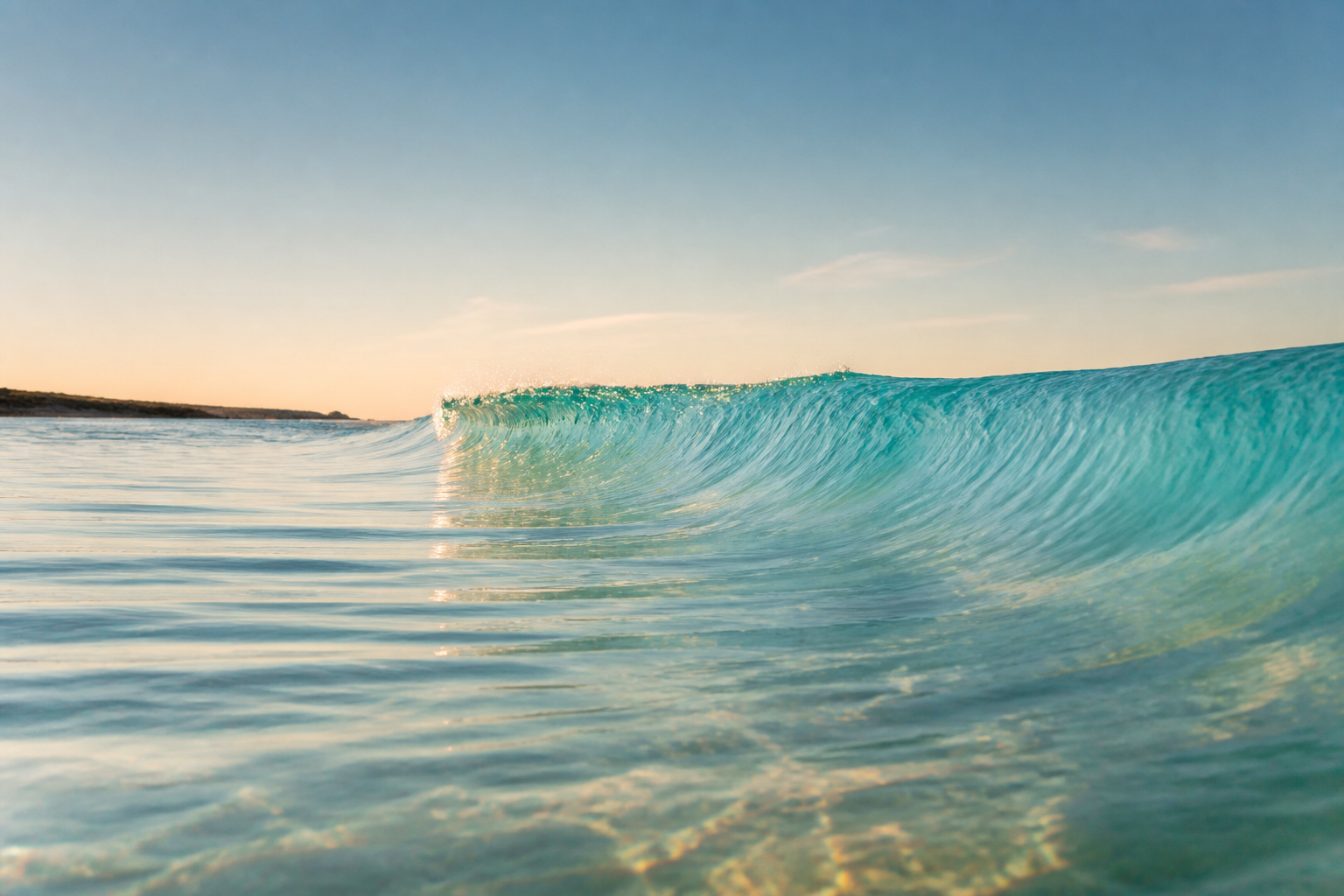 A clear turquoise wave in warm morning light